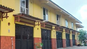 A row of yellow buildings with black doors and a tiled walkway. - Hotel Kayu Manis (Pakem)
