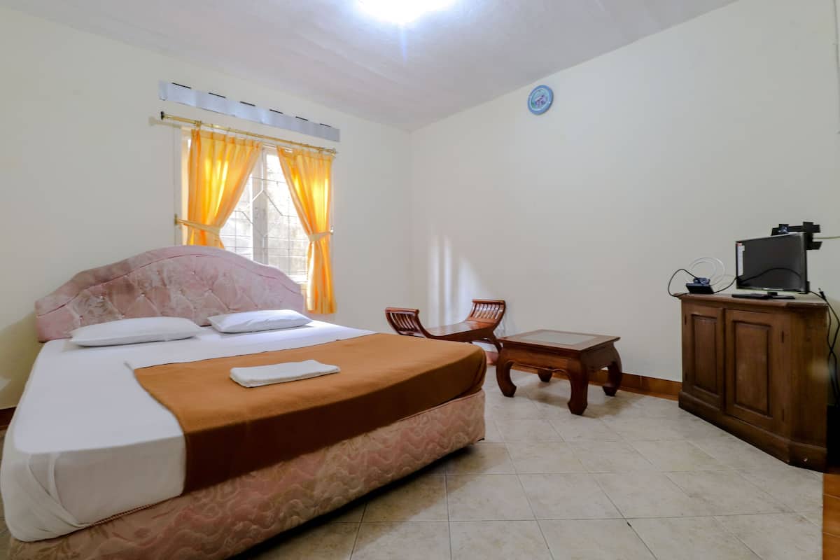 A hotel room with a bed, a desk, a chair, and a television.