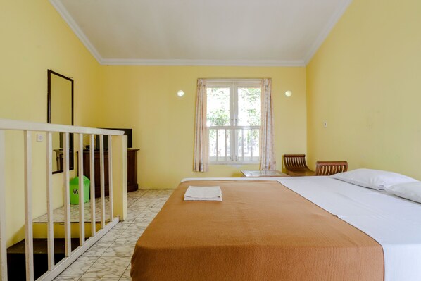 Una habitación con una cama, una ventana con cortinas, una mesita y una silla.
