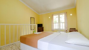 A room with a bed, a wooden chair, a television, and a window with curtains. - Hotel Kayu Manis (Pakem)