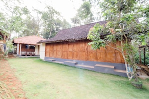 A traditional wooden house with a tiled roof, a small porch, and a well-maintained lawn.