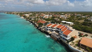Une ville côtière avec des bâtiments qui bordent le littoral, un ciel dégagé et des eaux turquoise.
