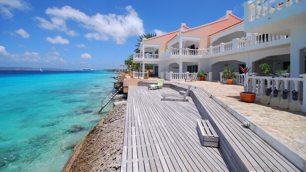 Un hôtel situé en bord de mer, doté d’une terrasse en bois, de plusieurs balcons et offrant une vue dégagée sur l’océan.