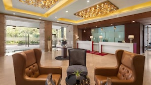 Un hall con sillones de cuero, una recepción y un techo decorativo.