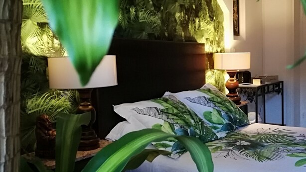 A bedroom with a bed, two bedside tables, a nightstand, a lamp, and a large potted plant. - Clos Germanois (Saint-Germain-Laval)