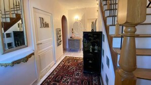 A hallway with a patterned carpet, a staircase, and a black refrigerator with decorative figures. - Clos Germanois (Saint-Germain-Laval)