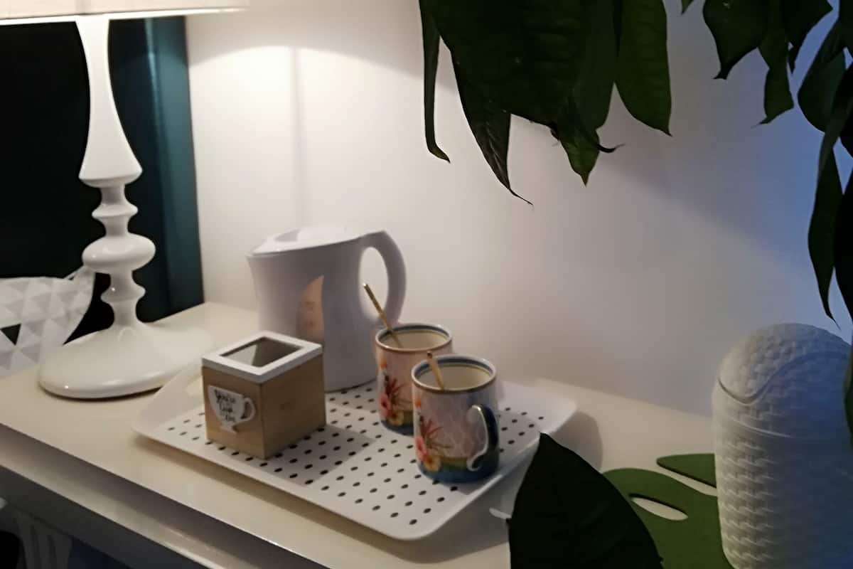 Una mesa con una lámpara blanca, dos tazas, una caja y un recipiente blanco.