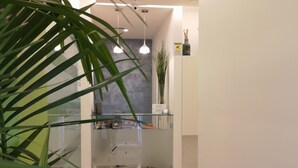 Et moderne receptionsområde med en glasvæg, en potteplante og et skilt, der angiver et område med forsigtighed.