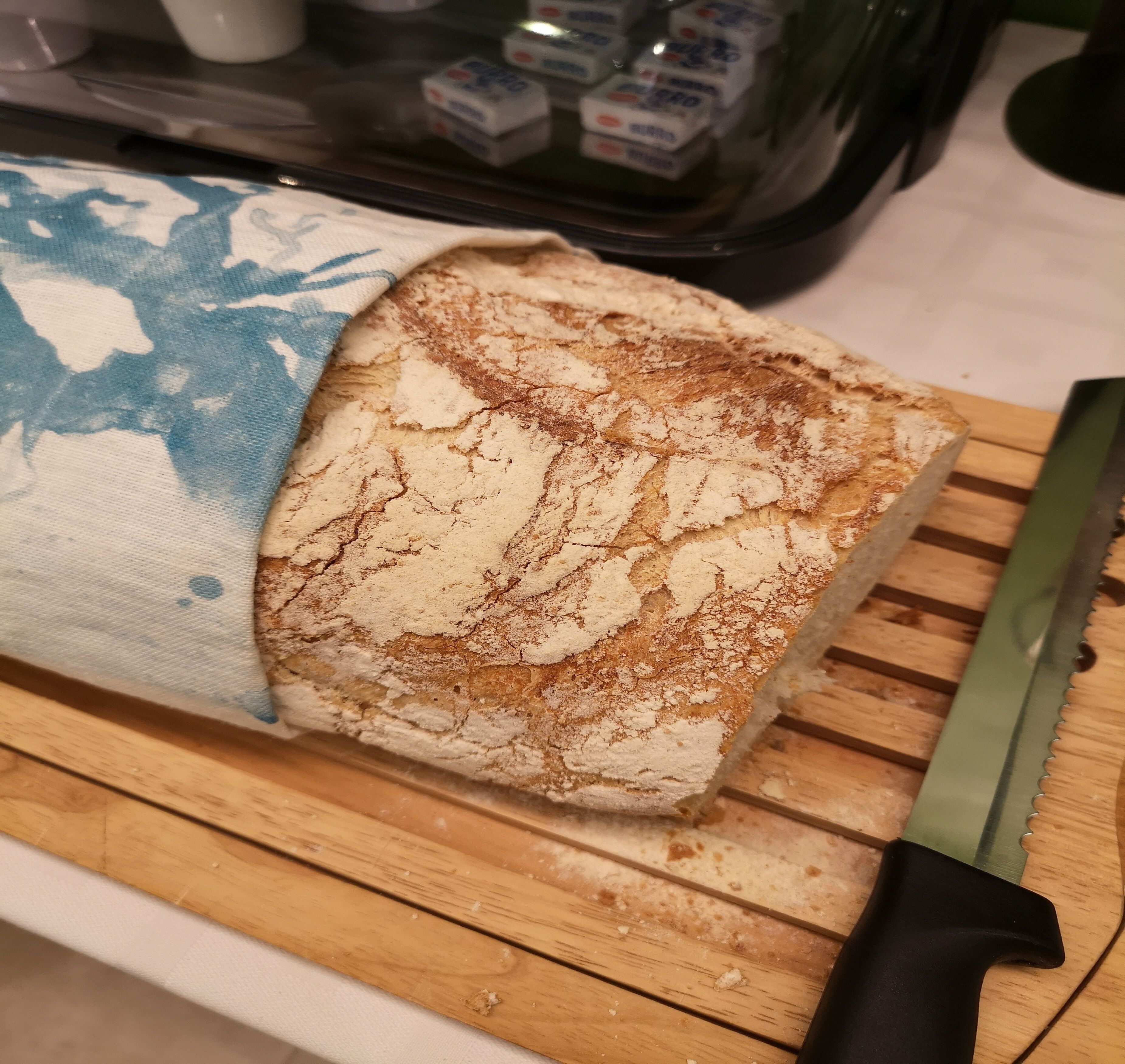 A loaf of bread on a wooden cutting board with a knife.