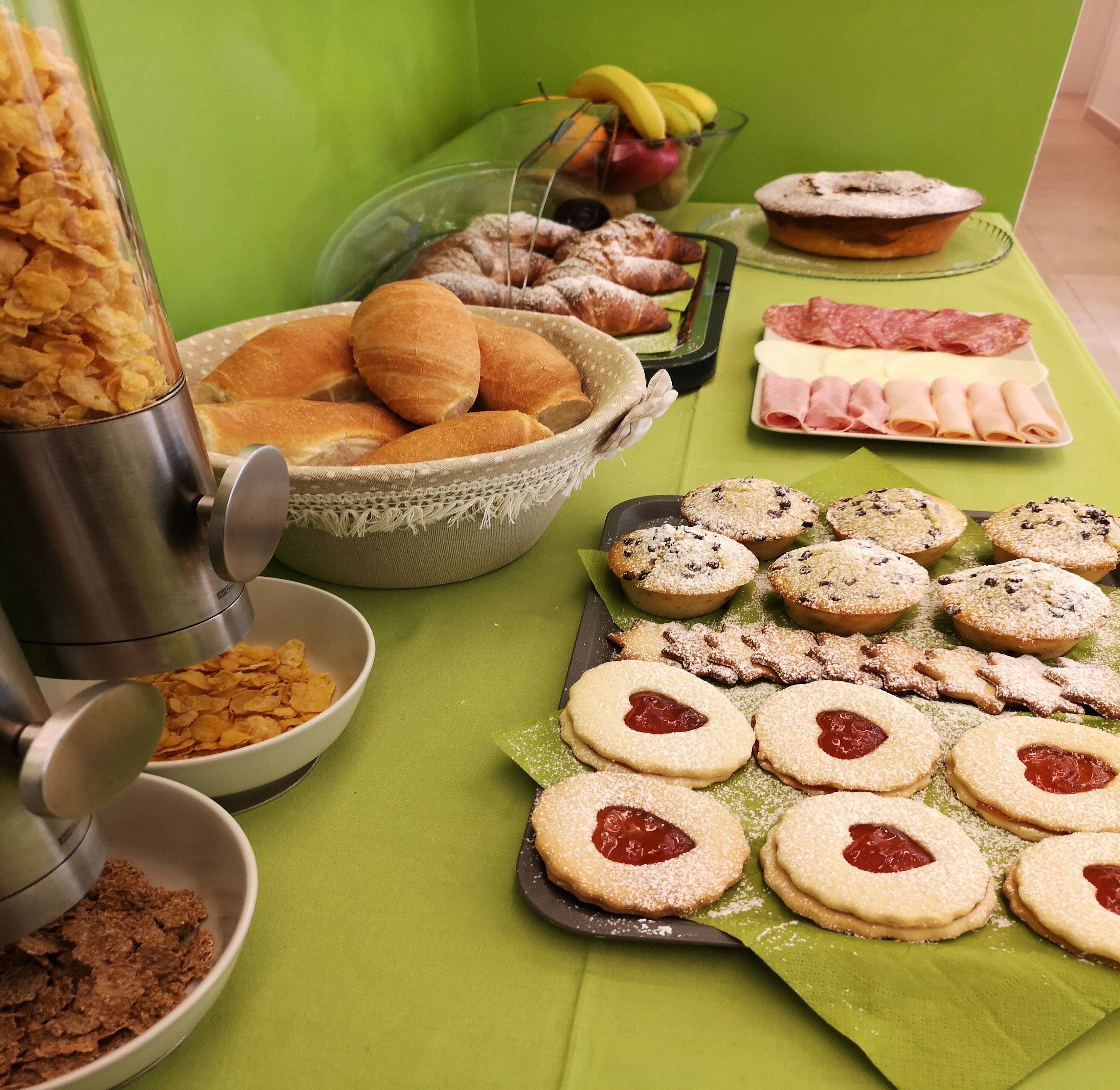 Una mesa de buffet con diversos alimentos, incluyendo pasteles, galletas y un bol de fruta.