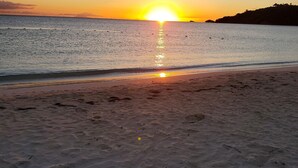 A beach with a sunset over the ocean.