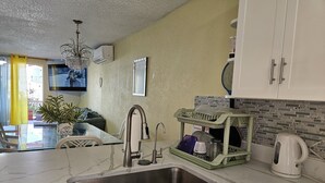 A kitchen with a marble countertop, stainless steel sink, and a dish rack.