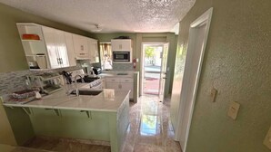A kitchen with a large island, white cabinets, a microwave, and a gas stove.