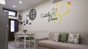 Un salon avec un canapé beige, des coussins verts et une décoration murale sur laquelle on peut lire « Cortile Davi ».