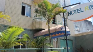 A hotel with a tiled facade, a sign indicating it is a hotel, and a palm tree in the foreground. - Hotel Rey (Camaçari)