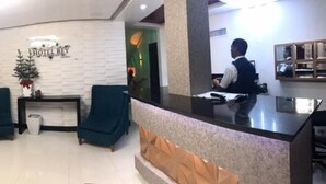 A hotel lobby with a reception desk, two armchairs, a fireplace, and a staircase. - Hotel Rey (Camaçari)