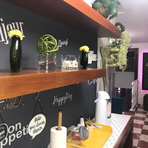 Una habitación con pared negra, texto decorativo y estante de madera con varios objetos.