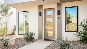 A modern building with a large glass window, a door with a number 24, and a small garden area with plants.
