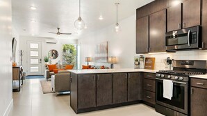 A modern kitchen with dark cabinetry, stainless steel appliances, and pendant lighting.