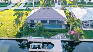 A residential property with a swimming pool, dock, and well-maintained lawn. - Marco Island Pool Home with Water View and Direct Access to the Gulf (Marco Island)