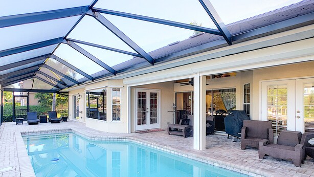 A covered swimming pool with lounge chairs and a barbecue area. - Marco Island Pool Home with Water View and Direct Access to the Gulf (Marco Island)