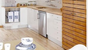 Uma cozinha moderna com armários brancos, detalhes em madeira e uma área de jantar com mesa e cadeiras.