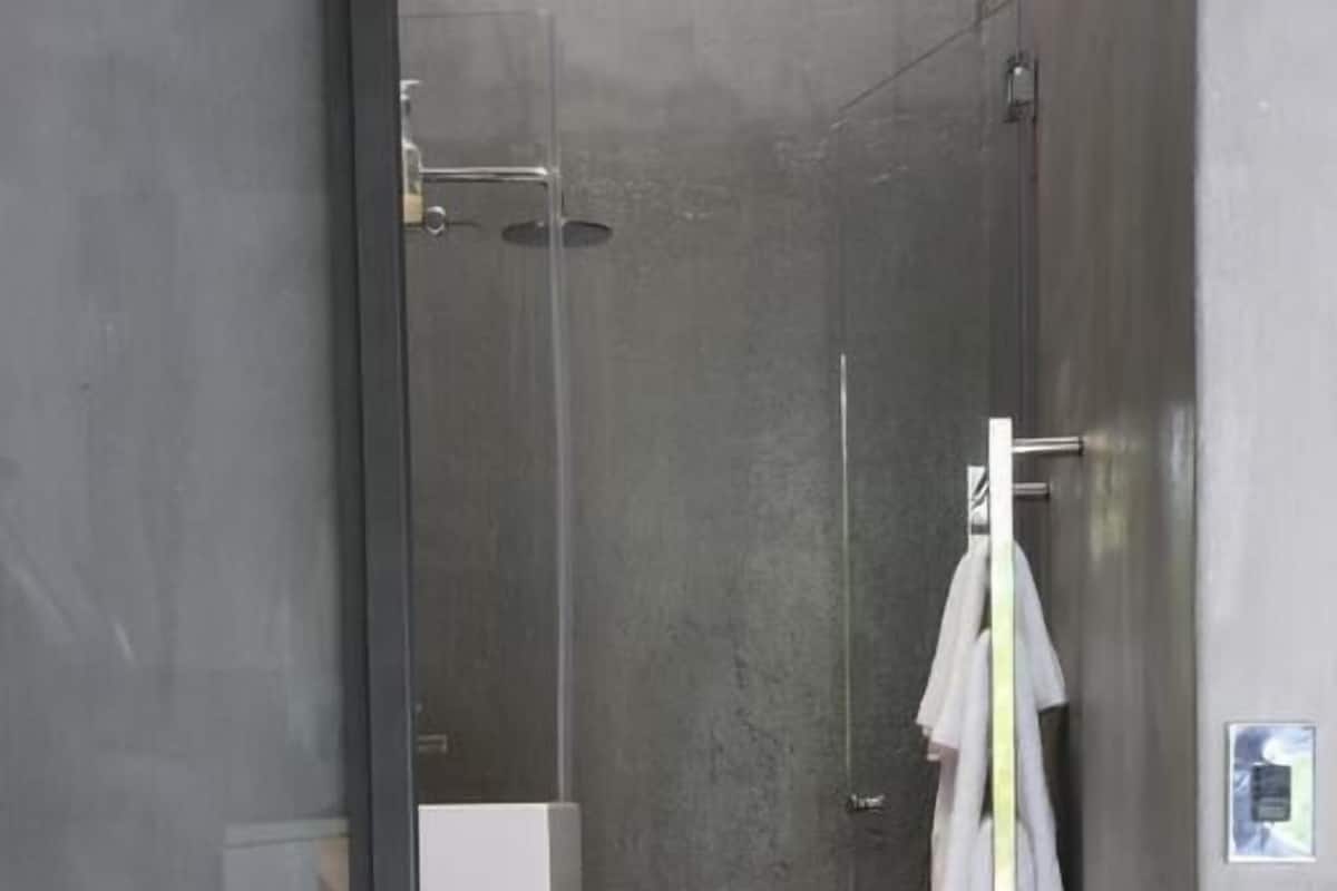 Une salle de bain moderne avec une douche à parois de verre, un porte-serviettes blanc et un sol recouvert d’une moquette rouge.