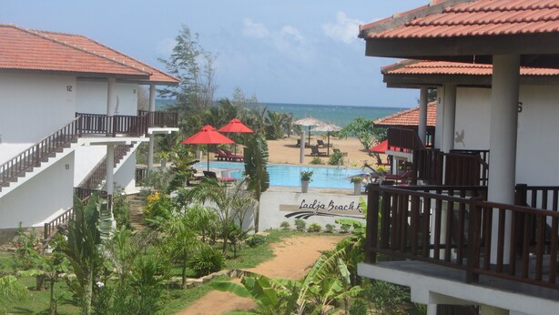 A resort with a pool, beach umbrellas, and a view of the ocean. - Ladja Beach Resort (Ambalantota)