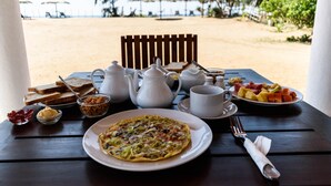 A breakfast table with a plate of food, a jug of milk, a cup, and a bowl of jam. - Ladja Beach Resort (Ambalantota)