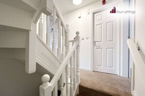 A staircase with white balusters leading to a door.
