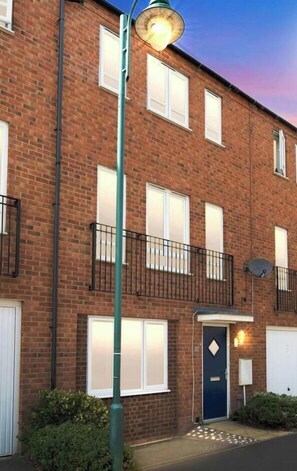 Un immeuble d’appartements en briques, doté de nombreuses fenêtres, d’une porte bleue et d’un lampadaire.