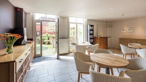 A modern kitchen with a dining area, large windows, and a view of the garden.