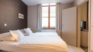 Een hotelkamer met een groot bed, een televisie en een raam met gordijnen.