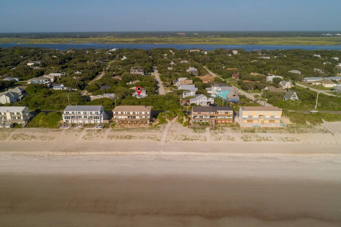 Vista aérea de una zona residencial costera con casas, una playa y una masa de agua.
