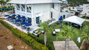 Un edificio blanco con un patio techado, mesas al aire libre y palmeras.