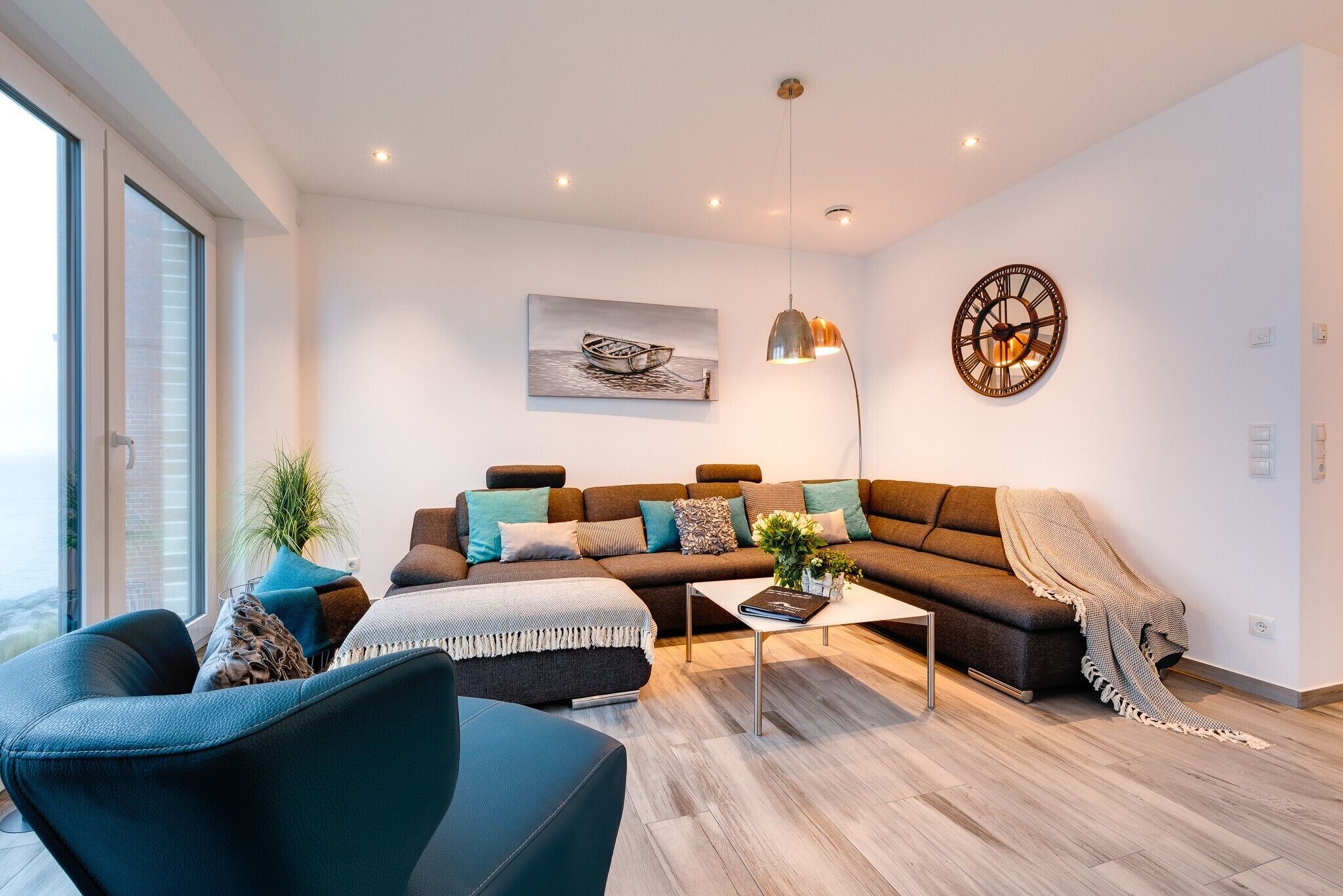 A modern living room with a sofa, armchairs, a coffee table, and a painting on the wall.