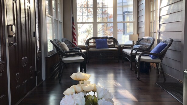 A sunlit porch with wicker furniture, a flag, and a floral arrangement. - Atlantic City Beach Retreat, Casino Fun, & 5-Min Walk to the Beach (Atlantic City)