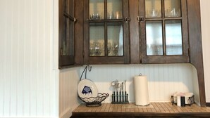 A kitchen with wooden cabinets, a white countertop, and a hanging dish rack. - Atlantic City Beach Retreat, Casino Fun, & 5-Min Walk to the Beach (Atlantic City)