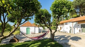 A hammock in a grassy area with a white building in the background.