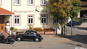 A hotel with outdoor seating, a classic car, and a sign indicating a 30 km/h speed limit. - Metzgereigasthof Rebstock (Ettenheim)