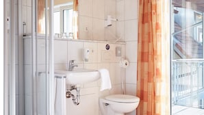 A bathroom with a glass shower enclosure, a sink, a toilet, and a mirror. - Metzgereigasthof Rebstock (Ettenheim)