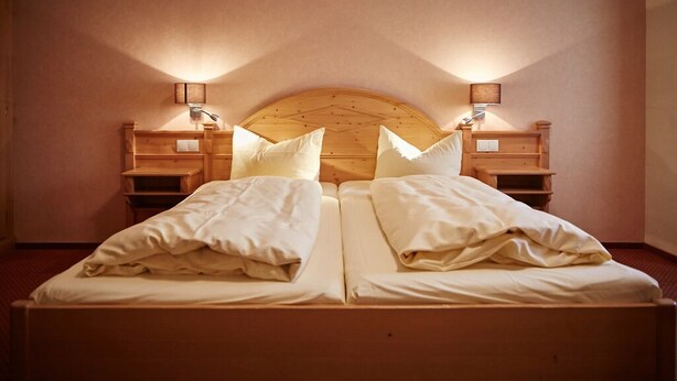 A double bed with wooden headboard and nightstands, each with a lamp. - Metzgereigasthof Rebstock (Ettenheim)