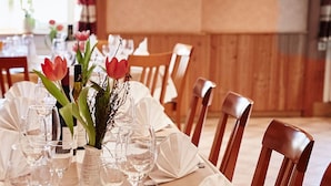 A dining table set with chairs, a vase with flowers, and wine glasses. - Metzgereigasthof Rebstock (Ettenheim)
