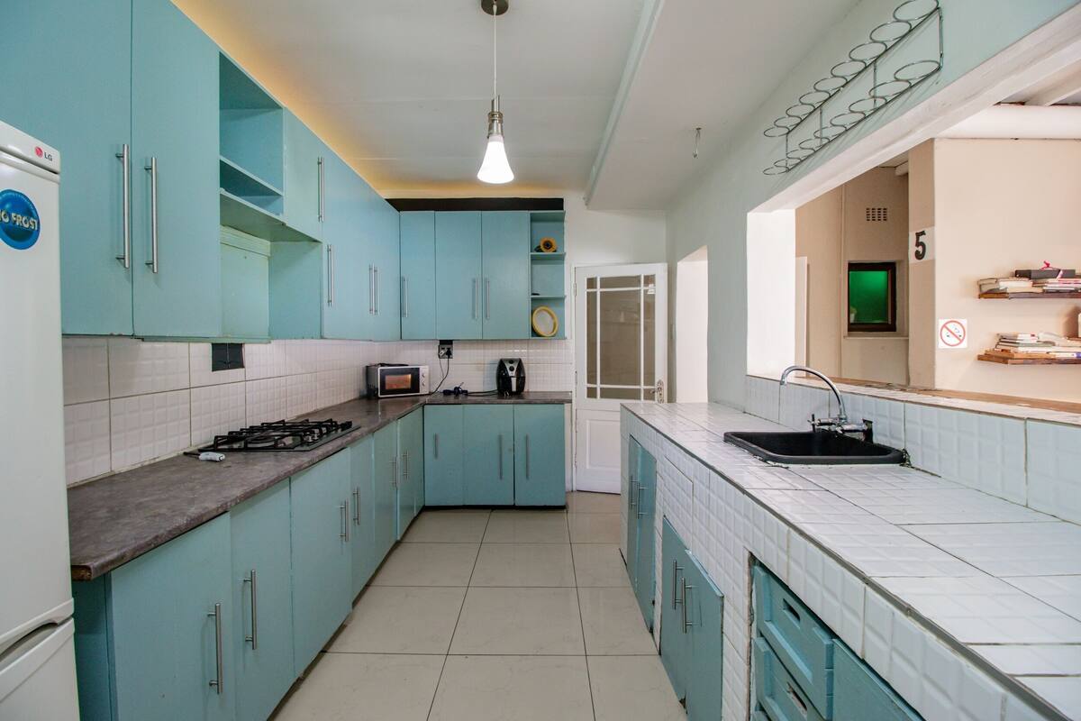 Une cuisine avec des armoires de couleur turquoise, un dosseret de carrelage blanc, une cuisinière à gaz et un évier.