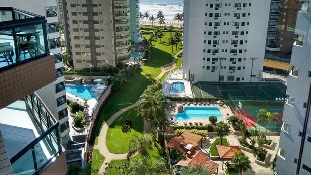 A high-rise hotel with multiple floors, a swimming pool, and a tennis court. - Beautiful fit, standing on the sand with spectacular sea views. Spotless (Bertioga)