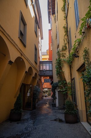 A narrow cobblestone alley flanked by buildings with arched doorways and windows, suggesting a historic or traditional setting. - Hotel Roma (Bologna)