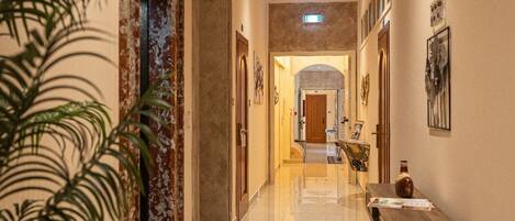 A hotel corridor with a polished floor, a reception desk, and framed artwork on the walls.