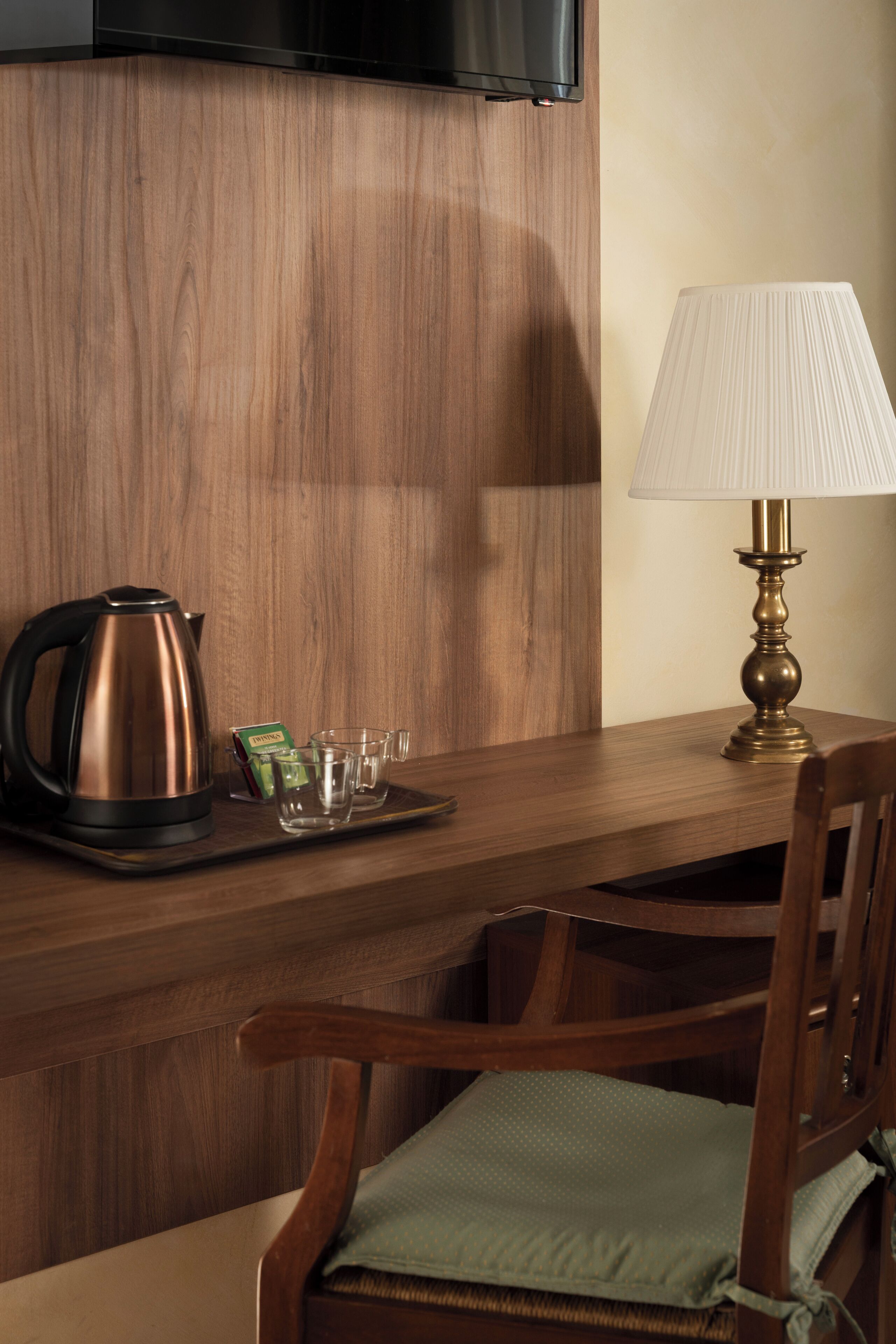 A wooden table with a kettle, a lamp, and a tray with glasses and a box.