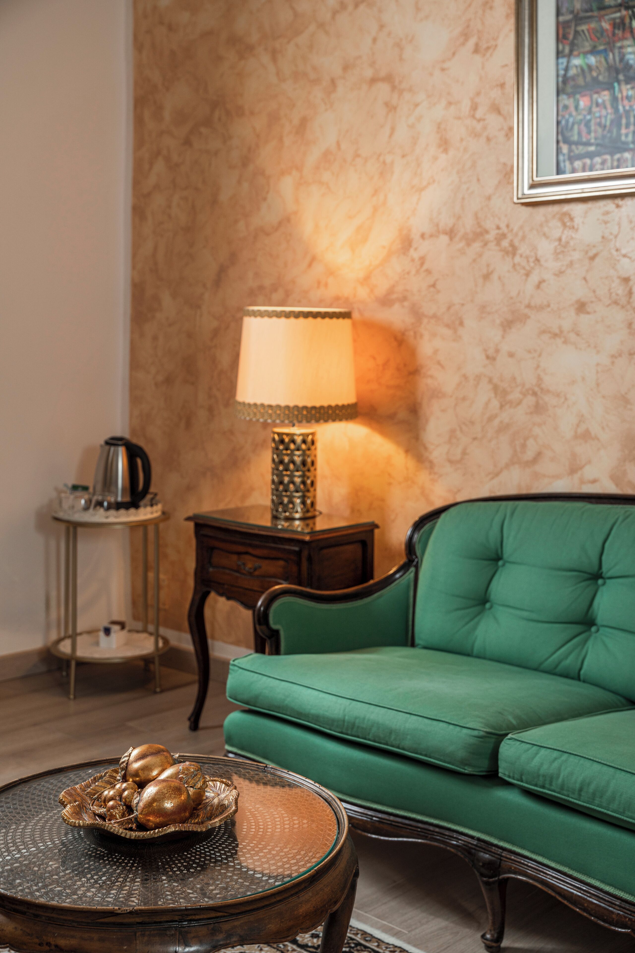 A green sofa, a lamp, a coffee table, and a patterned wall.