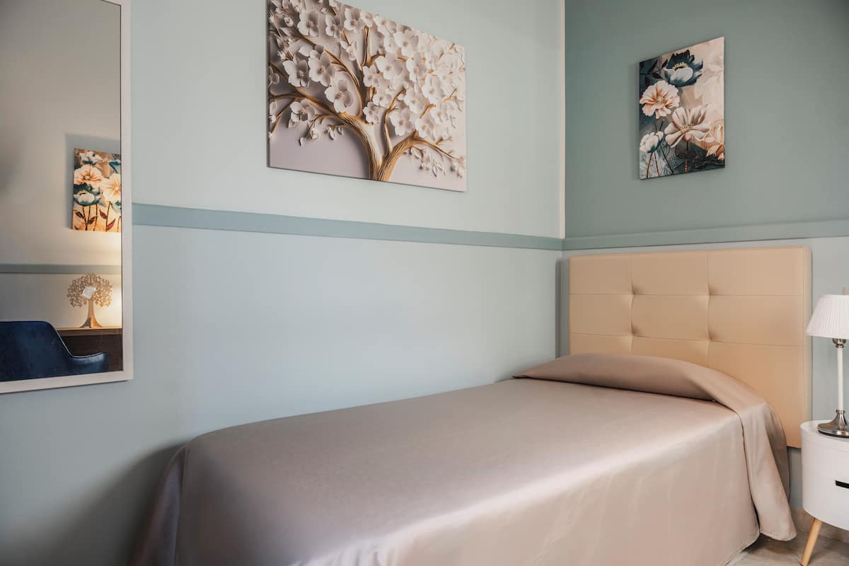 Un dormitorio con cama, mesita de noche, lámpara y decoración en la pared.